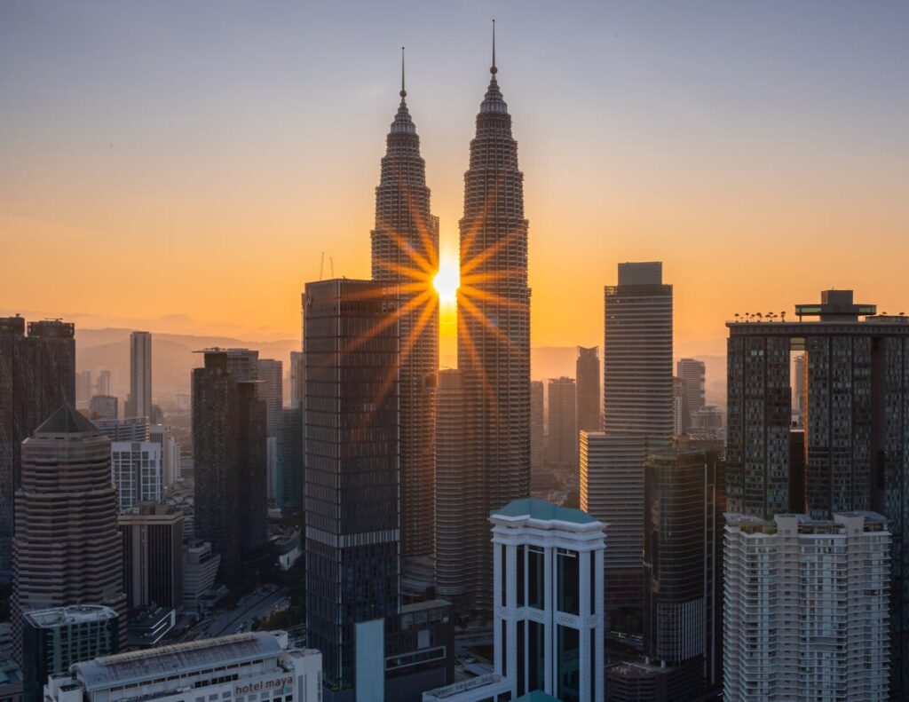 Capture of the iconic Petronas Towers with the sun setting in Kuala Lumpur's skyline.